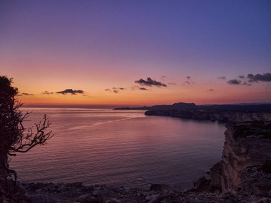 Bonifacio şehrinde gün batımı, Fransa 'nın Korsika adasındaki Akdeniz' in turkuaz suyuyla çevrili beyaz kayalıklarda uzanıyor.