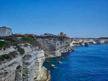 Bonifacio şehri, Fransa 'nın Korsika adasındaki Akdeniz' in turkuaz suyuyla çevrili beyaz bir uçurumun üzerinde uzanıyor.