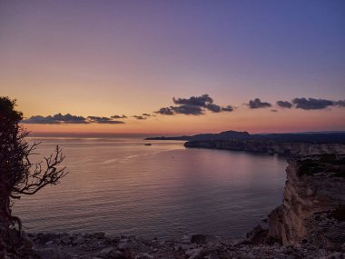 Bonifacio şehrinde gün batımı, Fransa 'nın Korsika adasındaki Akdeniz' in turkuaz suyuyla çevrili beyaz kayalıklarda uzanıyor.