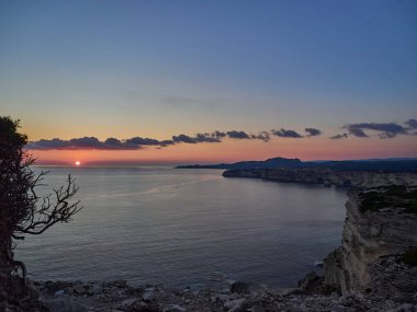 Bonifacio şehrinde gün batımı, Fransa 'nın Korsika adasındaki Akdeniz' in turkuaz suyuyla çevrili beyaz kayalıklarda uzanıyor.
