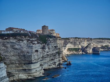 Bonifacio şehri, Fransa 'nın Korsika adasındaki Akdeniz' in turkuaz suyuyla çevrili beyaz bir uçurumun üzerinde uzanıyor.