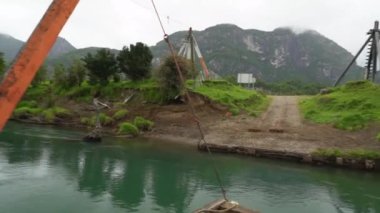 Patagonya, Şili 'de Carretera austral boyunca küçük bir nehri geçen küçük turuncu bir feribot.