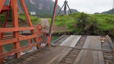 Patagonya, Şili 'de Carretera austral boyunca küçük bir nehri geçen küçük turuncu bir feribot.
