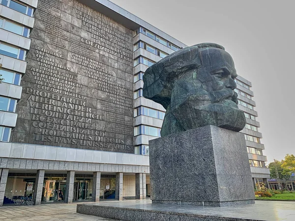 Chemnitz, Almanya - 09 08 2021: Karl Marx anıtı, taşa kazınmış büyük harflerle komünist tezinin metnini gösteren bir binanın önünde.