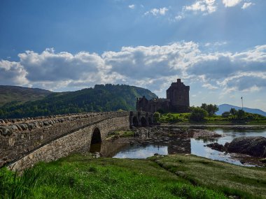 Eilean Donan, İskoçya - 05: 26 2018: Kuzey İskoçya kıyılarındaki tarihi ve tarihi bir Eilean şatosu. Güneşli bir günde Atlantik okyanusunun sakin sularında yansımaları var..