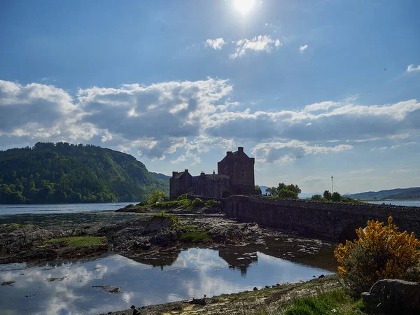 stock image Eilean Donan, Scotland - 05 26 2018: old and historical eilean donan castle at the coastline of northern Scotland on a sunny day with reflections in the calm water of the atlantic ocean.