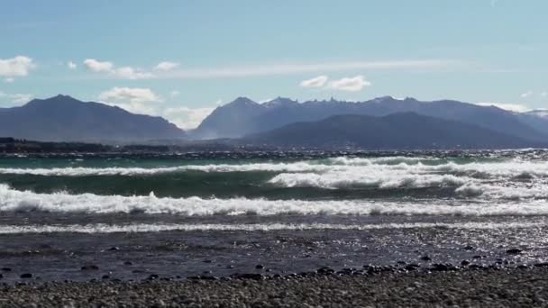 風の強い日にナウエル フアピ湖に上陸した波の動きが遅いパタゴニアでサン カルロス バリローチェを背景に — ストック動画