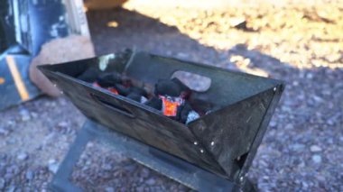 Gün batımında Şili 'deki Atacama Çölü' nde kumlu bir düzlükte parlayan ve yanan sıcak kömürle küçük ve katlanabilir ızgara ocağı..