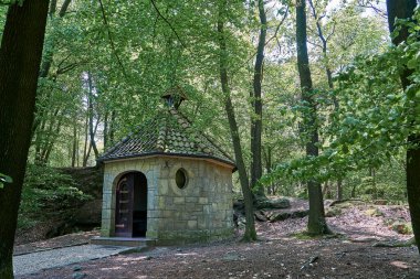 Almanya 'nın Tecklenburg kentinin çevresindeki Teutoschleifen yürüyüş yolu boyunca uzanan küçük bir taş şapelin önünde..