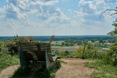 Almanya 'da Tecklenburg yakınlarındaki Teuroschleifen yürüyüş parkurunda yürüyüş yaparken bir bankta oturan tanınmamış genç bayan yürüyüşçü..
