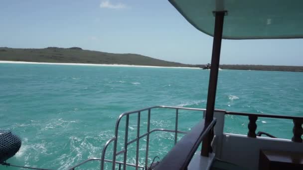 太平洋のターコイズ海水を介してガラパゴス諸島の白い砂浜に沿ってクルーズする小さなモーターヨット — ストック動画