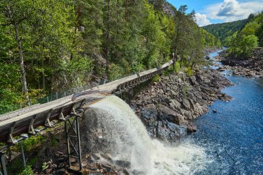 Norveç 'in güneyinde Vennesla yakınlarındaki Tommerrenna' nın tarihi restore edilmiş ahşap sal kanalı ya da kereste kaydırağı yürüyüşçüleri için popüler bir yerdir.