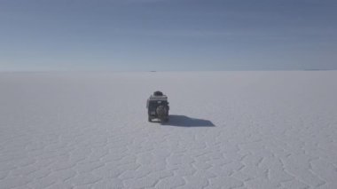 Pescado adasının etrafındaki Salar de Uyuni tuzlu gölüne giden 4x4 'lük bir aracın insansız hava aracı görüntüsü. Bolivya' daki And Dağları 'nın yüksek irtifasında, dünyanın en büyük tuz tabakası..