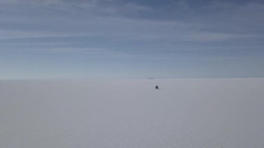 Pescado adasının etrafındaki Salar de Uyuni tuzlu gölüne giden 4x4 'lük bir aracın insansız hava aracı görüntüsü. Bolivya' daki And Dağları 'nın yüksek irtifasında, dünyanın en büyük tuz tabakası..
