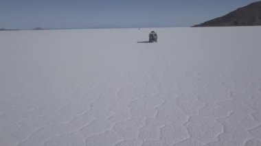 Pescado adasının etrafındaki Salar de Uyuni tuzlu gölüne giden 4x4 'lük bir aracın insansız hava aracı görüntüsü. Bolivya' daki And Dağları 'nın yüksek irtifasında, dünyanın en büyük tuz tabakası..