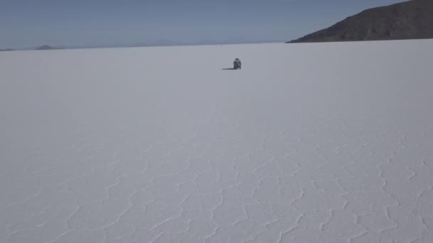 在玻利维亚安第斯山脉高海拔的世界上最大的盐滩上 一架四轮驱动越野车在鱼岛附近的Salar Uyuni盐湖上驾驶 无人驾驶飞机对该车辆进行了射击 — 图库视频影像