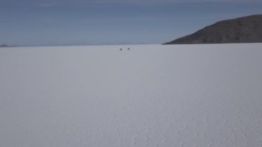 Pescado adasının etrafındaki Salar de Uyuni tuzlu gölüne giden 4x4 'lük bir aracın insansız hava aracı görüntüsü. Bolivya' daki And Dağları 'nın yüksek irtifasında, dünyanın en büyük tuz tabakası..