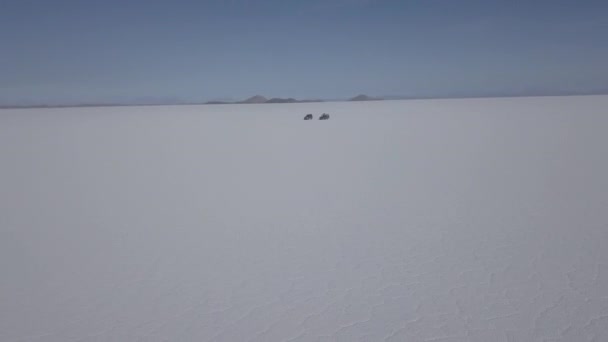 在玻利维亚安第斯山脉高海拔的世界上最大的盐滩上 一架四轮驱动越野车在鱼岛附近的Salar Uyuni盐湖上驾驶 无人驾驶飞机对该车辆进行了射击 — 图库视频影像
