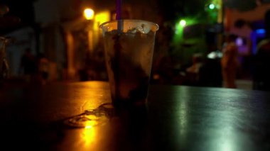 Plastik bardakta buz gibi Caipirinha Kokteyli, Cartagena 'da tarihi Getsemani bölgesinin sokaklarında, tahta bir masanın üzerinde duruyor..