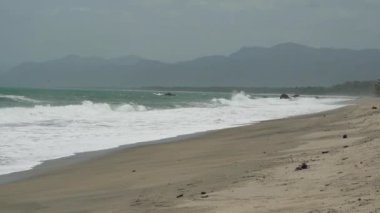 Dalgalar, Kolombiya 'daki Sierra Nevada de Santa Marta' daki Atlantik Okyanusu 'nun tropikal kıyısı boyunca Tayrona Ulusal Parkı yakınlarındaki beyaz kumsala çarpıyor..