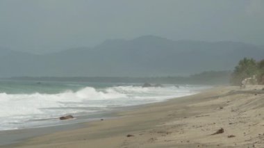 Dalgalar, Kolombiya 'daki Sierra Nevada de Santa Marta' daki Atlantik Okyanusu 'nun tropikal kıyısı boyunca Tayrona Ulusal Parkı yakınlarındaki beyaz kumsala çarpıyor..