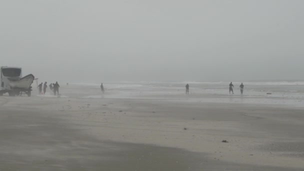密集した霧を通って大西洋の広い砂浜を歩く漁師 — ストック動画