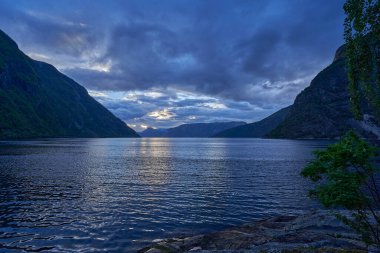 Norveç 'in arka planında sakin yeşil suları ve dağları kaplayan karla kaplı Hardanger fiyordunun güzel sakin manzarası..