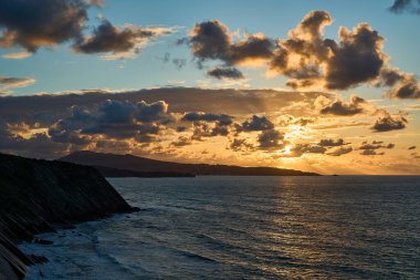 St. Jean de Luz yakınlarındaki Bisscay körfezinin sarp ve engebeli uçurumlarında Fransa ve İspanya arasındaki sınırda dramatik günbatımı ve bulutlu manzarayla.