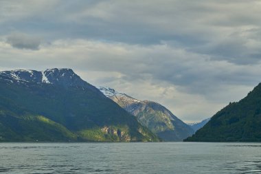 Norveç 'in arka planında sakin yeşil suları ve dağları kaplayan karla kaplı Hardanger fiyordunun güzel sakin manzarası..