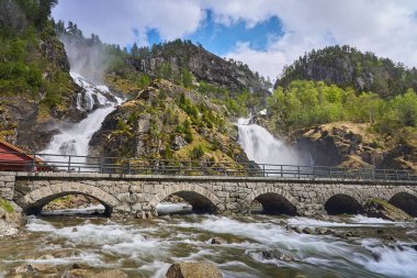 Norveç 'in Odda yakınlarındaki muhteşem Latefossen şelalesinin yanından geçen eski bir taş köprü..