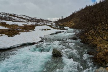 Aurlandsvegen 'in dağlık arazilerindeki canlı bir nehrin vahşi beyaz suları Norveç' in görkemli manzarasını aşıyor..