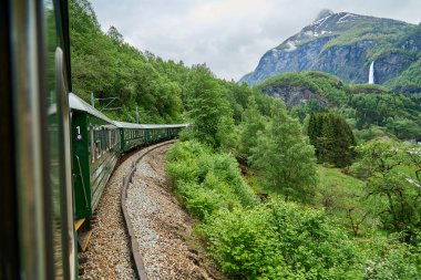 Flam, Norveç - 06 03 2022: Flamsbana ile Aurland 'daki Flam ve Myrdal arasındaki en güzel tren yolculuğunun görüntüsü deniz seviyesinden dağlara uzanan muhteşem bir vadiden geçiyor..