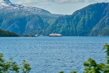 Tipik Norveç otomobil feribotu dağların arasındaki güzel fiyortta güneşli bir günde Geiranger 'e giden yolcu ve arabaları taşıyor.,