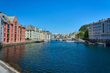 Alesund, Norveç - 06 07 2022: Norveç 'in Atlantik Okyanusu kıyısı boyunca uzanan Alesund şehir merkezindeki güzel liman mavi su ve renkli evlerle dolu güneşli bir günde.