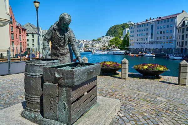 Alesund, Norveç - 06 07 2022: Alesund Kanalı 'nın güzel limanı ve Sildekona ringa eş heykeli, arka planda renkli Art Nouveau mimarisi.