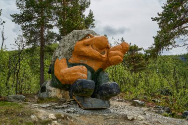 Telemark, Norveç - 06: 15 2022: Norveç 'in dağlık kesimlerinde bir patikanın yanında oturan ve bir şeyi işaret eden Trol heykeli.