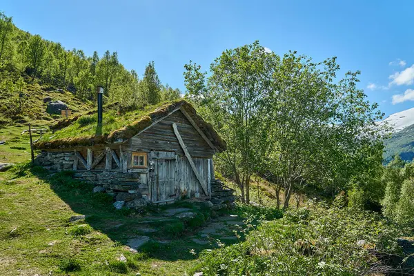 old hut along the hiking trail towards the spectacular Seven Sisters waterfall through deep green forest along the Geirangerfjord, Norway on a sunny day.