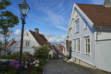 Stavanger, Norveç - 05: 29: 2022: Rogaland, Norveç 'te Gamle Stavanger' da güzel geleneksel beyaz ahşap evleri olan tarihi cadde, güneşli bir gün.