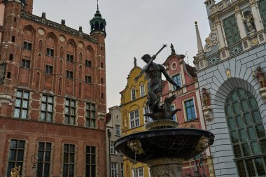 Neptune fountain in Gdansk, Pomerania, Poland. Sculpture and fountain of a roman god with trident in old town of Danzig in front of historical buildings. clipart