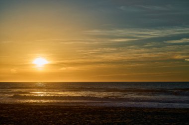 Dalgalar, Portekiz 'in Porto yakınlarındaki Atlantik Okyanusu' nun sahil şeridi boyunca uzanan plajda romantik bir gün batımında kıyıya vuruyor..