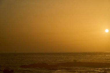 Portekiz 'in engebeli ve kayalık kıyı şeridi boyunca derin mavi Atlantik Okyanusu' nda seyreden küçük yelkenli bir tekne..