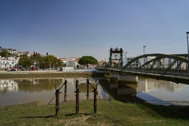 Portekiz 'in Lizbon kenti yakınlarındaki tipik beyaz evleri ile Sado nehri kıyıları boyunca uzanan tarihi Alcacer kenti yakınlarındaki su üzerindeki köprü, Güney Avrupa' da popüler bir seyahat merkezi..