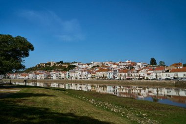 Portekiz 'in Lizbon kenti yakınlarındaki tipik beyaz evleri ile Sado Nehri kıyıları boyunca tarihi Alcacer do Sal şehri, Güney Avrupa' nın popüler bir tatil beldesi..