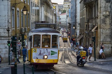 Lizbon, Portekiz - 10 7 2022: Lizbon sokaklarındaki tipik eski sarı vintage tramvay dar sokaklarda ilerliyor.