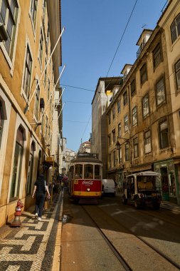 Lizbon, Portekiz - 10 7 2022: Lizbon sokaklarındaki tipik eski sarı vintage tramvay dar sokaklarda ilerliyor.