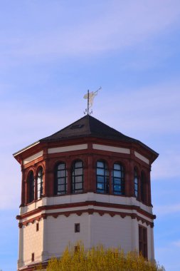 Çatıda birçok penceresi olan kırmızı ve beyaz bir bina, bir trompet görebilirsiniz.