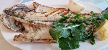 Kızarmış cupra, ikiye bölünmüş, limon ve salata yaprağı ile.