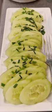 Dilimlenmiş salatalık ve dereotu beyaz tabakta.