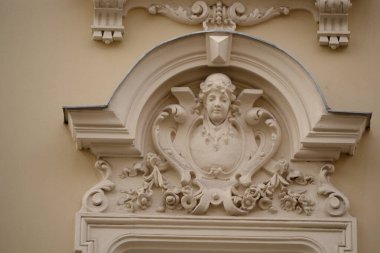 Bu Art Nouveau heykelinde çiçek motifleri tarafından çerçevelenmiş genç bir kadının sanatsal profili yer alıyor. Saçları zarif bir şekilde şekillenmiş ve yaprakların narin tasarımı 19. yüzyılın sonlarındaki kadınsı estetiği vurguluyor. Ustaca bir örnek 