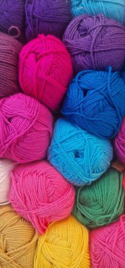 Yukarıdan aşağıya, çok sayıda canlı ve renkli ipliğin yakın plan görüntüsü. Dar yaralı iplik mor, pembe, mavi, yeşil, mor ve sarı gibi parlak ve zengin tonların bir karışımıdır..